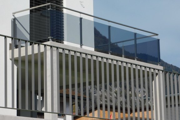 Balkongeländer; Chromstahlpfosten mit Glashalterungen, Füllungen in Glas mit Graufolie