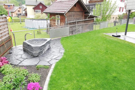 Gartenanlage; Wasserspeier zu Granitbrunnen, Grundstückabgrenzung mit Zaun in Chromstahldrahtgeflecht und Chromstahl-Blechfüllungen mit Laserausschnitten